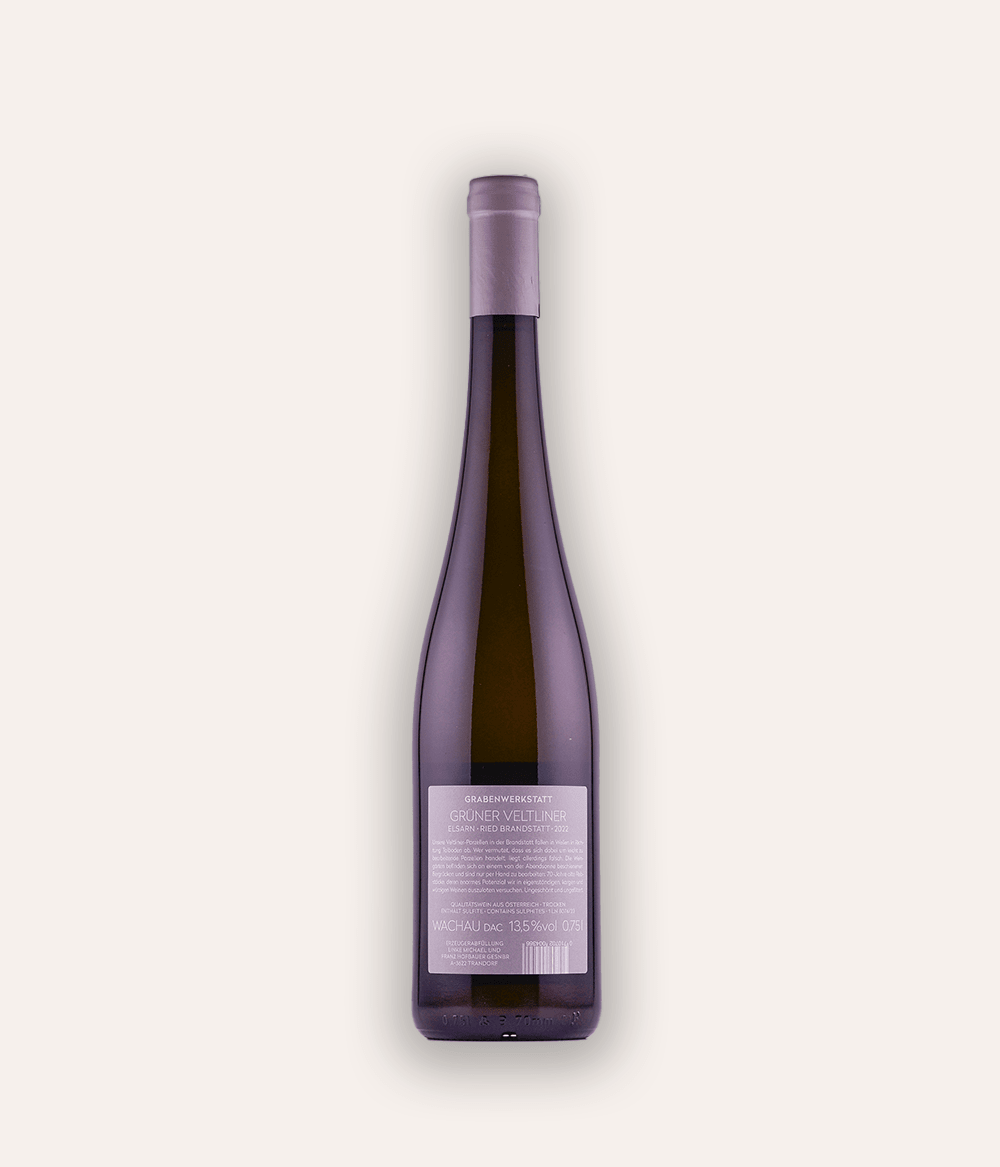 Rückseite der Weinflasche Grabenwerkstatt – Grüner Veltliner Ried Brandstatt 2022 – Wachau-Flasche mit lavendelfarbener Schraubkapsel, minimalistisches Etikett mit Grabenwerkstatt Lagebezeichnung und Wachau DAC