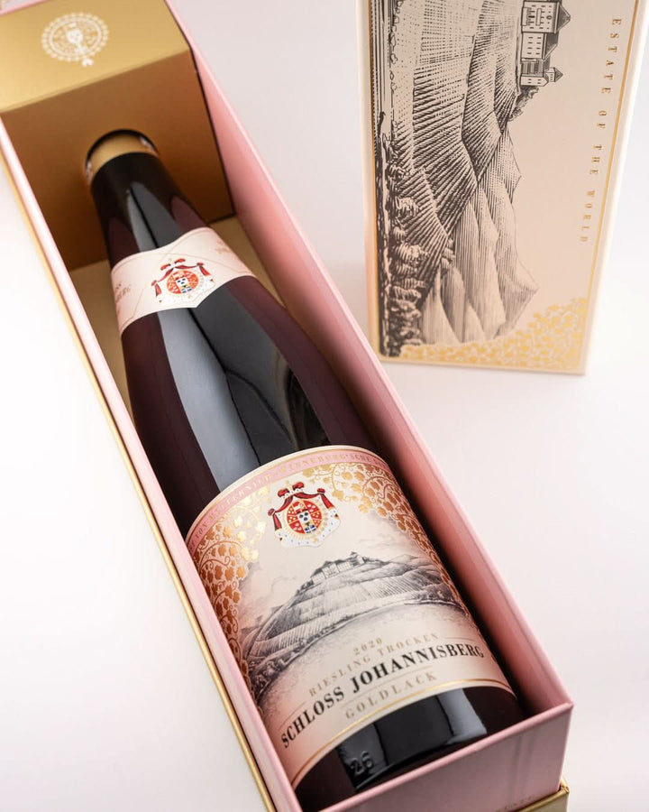 Weinflasche Schloss Johannisberg Riesling Goldlack 2020 in geöffneter pinker Geschenkbox, ornamentales Etikett mit Wappenschild; Außencover mit Kupferstich und Aufschrift The First Riesling Estate of the World